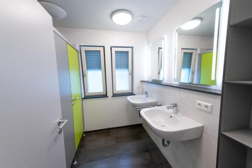 a bathroom with two sinks and two mirrors at Stadthaus Seeblick G5 - Hostel in Friedrichshafen