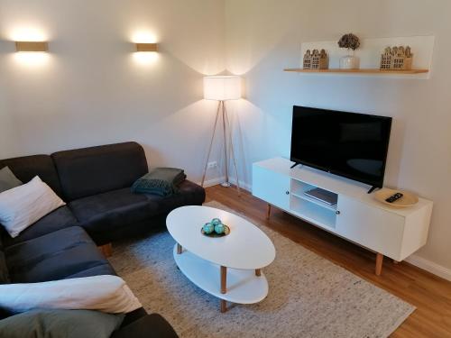 a living room with a couch and a tv and a table at Strohböhn in Oldendorf