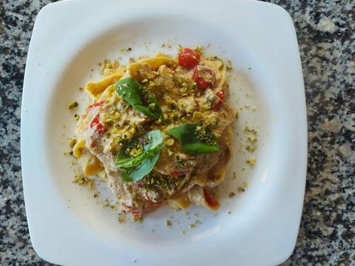 a white plate of pasta with vegetables and sauce at Agriturismo La Miniera in Gignese