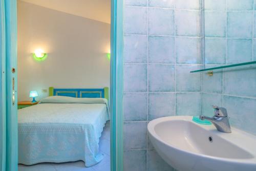a bathroom with a sink and a bed and a tub at Conchiglia Verde in Barrabisa