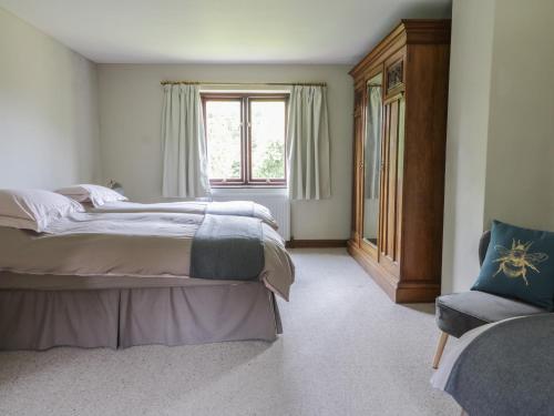 a bedroom with a bed and a window and a chair at Craven Cottage in Great Driffield