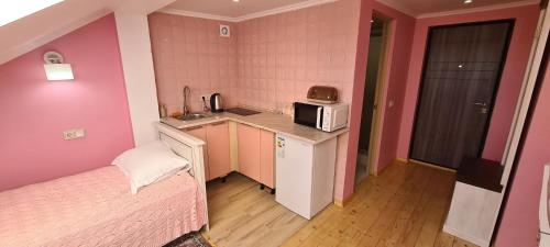 een kleine keuken met een bed en een magnetron bij Аpartment for Lady in Tsjernivsi