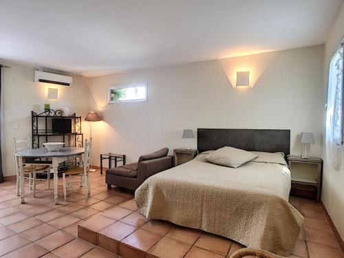 een slaapkamer met een bed, een tafel en een stoel bij Anne de la Maison Blanche in Avignon