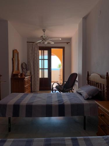 a bedroom with a bed and a chair and a window at Apartamento luminoso 1ª línea Arena Beach_Estepona in Estepona