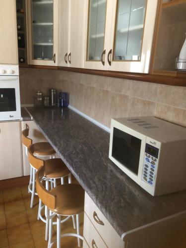 a kitchen with a counter with a microwave and stools at Casa con Gran Piscina particular cerca playa in Torredembarra