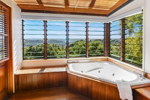 a bath tub in a room with windows at Rosebrook Cottages in Maleny