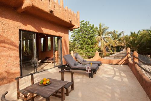 un patio con 2 sedie e un tavolo su una casa di Tama Lodge a M'bour