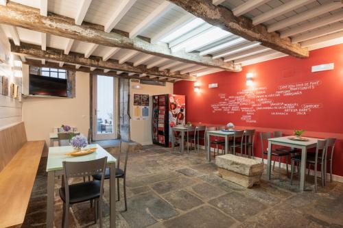 a restaurant with tables and chairs and a red wall at Albergue The Last Stamp in Santiago de Compostela