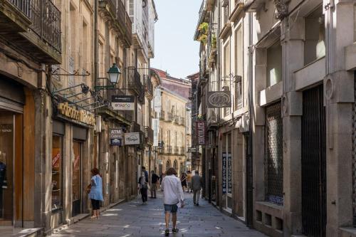 a group of people walking down a street with buildings at Albergue The Last Stamp in Santiago de Compostela