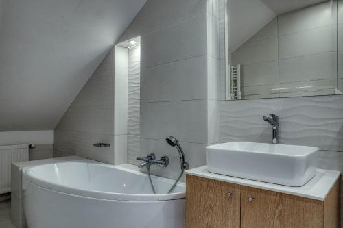 a white bathroom with a sink and a tub at Marina Club Residence in Gdańsk