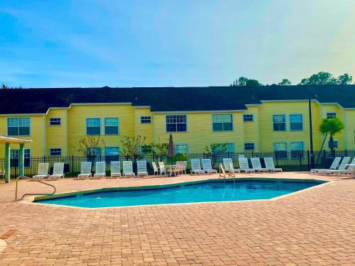 - un bâtiment jaune avec piscine et chaises longues dans l'établissement Grand Luxury 3BR Condo Apartment near Universal Studios, à Kissimmee