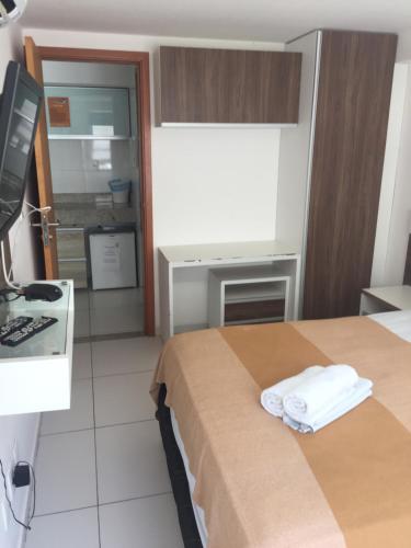 a hotel room with a bed and a desk with a computer at Melhor ponto turístico de Jampa Ap 119 in João Pessoa