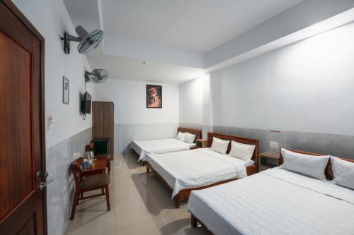 Habitación con 3 camas, mesa y silla en Thanh Ngọc Motel en Buon Ma Thuot