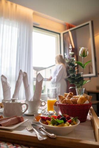 Una mesa con un plato de comida y una mujer junto a una ventana. en Logis Hotel Relais Saint Jacques - Châteauroux, en Déols