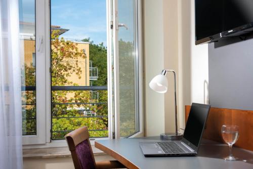a laptop sitting on a desk with a large window at Seminaris SeeHotel Potsdam in Potsdam