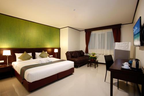a hotel room with a large bed and a couch at Orchid Resortel in Patong Beach