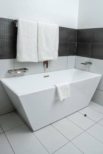 a white bath tub in a bathroom with black tiles at LOCH LOGAN HOTEL in Bloemfontein