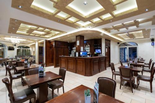 un restaurante con mesas y sillas y un bar en Garni Hotel Royal Crown en Subotica