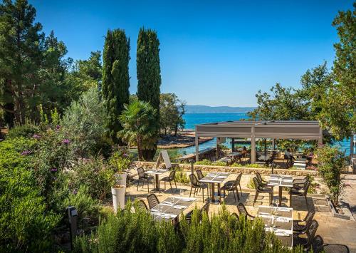 a restaurant with tables and chairs and the water at Veya Maradiso Hotel by Aminess in Njivice