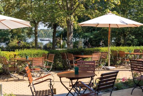 an outdoor patio with tables and chairs and umbrellas at Seminaris SeeHotel Potsdam in Potsdam
