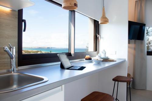 a kitchen with a laptop on a counter with a window at Gaviota - Emar Hotels Adults Only in Es Calo