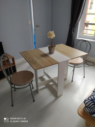 une table en bois avec deux chaises et une table avec un vase dans l'établissement le studio de la plage, à Trouville-sur-Mer