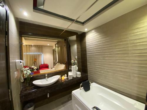 a bathroom with a sink and a tub and a mirror at Lahore Continental Hotel in Lahore