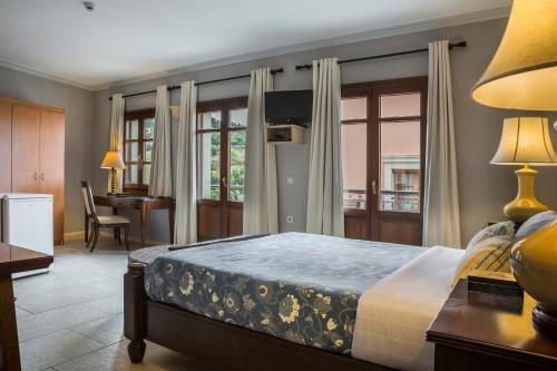 a bedroom with a bed and a table and a desk at Balhambra Suites - Adults Only in Fiskardho