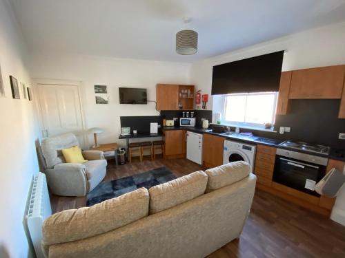 a living room with a couch and a kitchen at Stylish 2nd Floor Georgian Period Flat in Dumfries