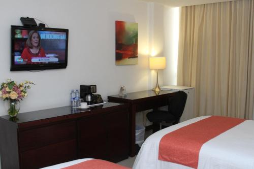 a hotel room with a desk and a television on the wall at Hotel Poza Rica Centro in Poza Rica de Hidalgo