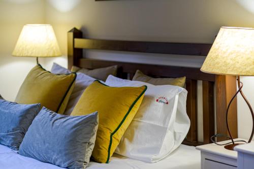a bed with yellow and blue pillows and two lamps at Studio Iviscos in Mikrón Khoríon