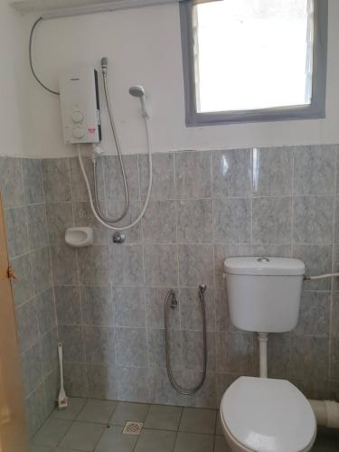 y baño con ducha y aseo. en Kinora Homestay en Perai