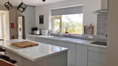 a kitchen with a counter with a sink and a window at TÍ Mhaggie Holiday Cottage by Trident Holiday Homes in Gowla