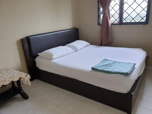 a bedroom with a bed with white sheets and a window at Kinora Homestay in Perai