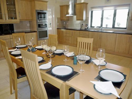 a kitchen with a wooden table with plates and wine glasses at Cnocan Na Cuaig Carraroe by Trident Holiday Homes in Carraroe