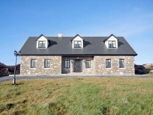a large stone house on a grassy field at Cnocan Na Cuaig Carraroe by Trident Holiday Homes in Carraroe