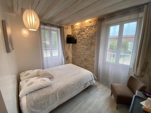 a bedroom with a bed and a window and a chair at La Ferme de Labbeville in Labbeville