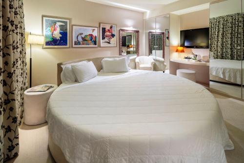 a bedroom with a large white bed and a bathroom at Base Hotel in Noventa di Piave