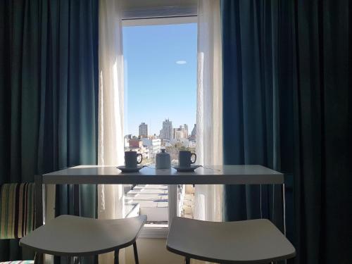 a table and two chairs in front of a window at ILLIA 121 APART HOTEL in Neuquén