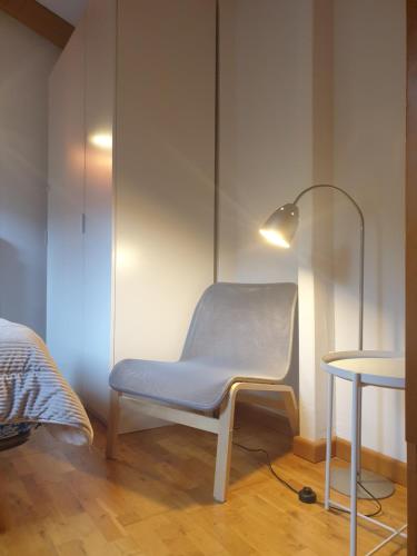 a blue chair in a room with a lamp and a bed at Dúplex Pla de L'Ermita (Boí Taüll) in Pla de l'Ermita
