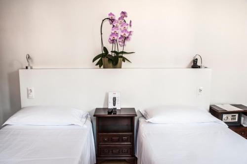 two beds with white sheets and a vase of flowers at Albergo Bologna in Varese