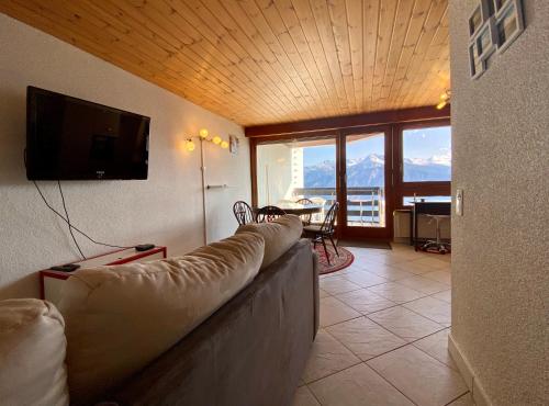 a living room with a couch and a flat screen tv at Résidences Kandahar in Crans-Montana