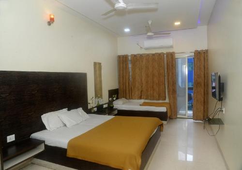 a hotel room with two beds and a window at Hotel Radhika Pune in Pune