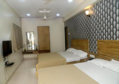 a hotel room with two beds and a television at Hotel Radhika Pune in Pune
