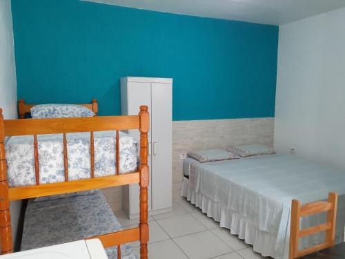 sypialnia z 2 łóżkami piętrowymi i niebieską ścianą w obiekcie Pousada Ancoradouro w mieście Cananéia