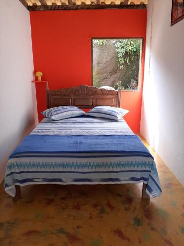 een bed in een kamer met een rode muur bij Ponta negra casa e chalé in Ponta Negra