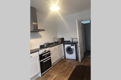 uma cozinha com um lavatório e uma máquina de lavar louça em Centrally located 1 bed modern flat with harbour views em Wick