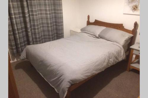 a bedroom with a bed with white sheets and a window at Centrally located 1 bed modern flat with harbour views in Wick