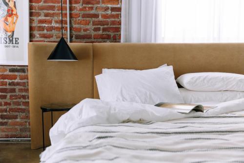 1 cama con sábanas blancas y almohadas junto a una pared de ladrillo en Maison Sainte-Thérèse By Maisons & co, en Montreal