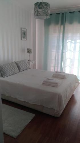 a bedroom with a large white bed with a window at Casa O'lado in Golegã